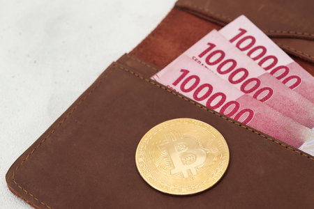 Bitcoin with one hundred thousand rupiah banknote on leather wallet. Cryptocurrency trading conceptの写真素材