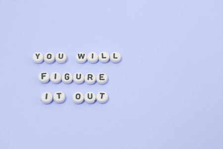 Top view of "You will figure it out" quotes made out of beads on pastel background. motivation and success conceptの写真素材
