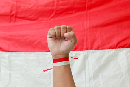 Close up of male hand with red and white ribbon raising up in the air fighting to celebrate...