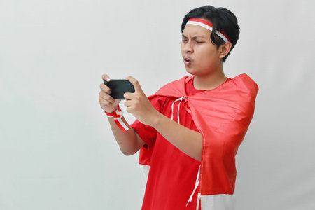 Portrait of attractive Asian man in t-shirt with red white ribbon on head with flag on his shoulder...