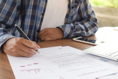Close up of freelance male hand filling official document, signing contract and tax. Document of...