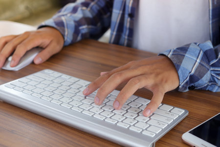 Close up of male hand using wireless keyboard and mouse in office desk. Casual working conceptの写真素材