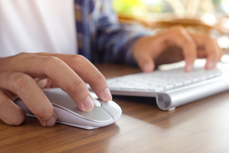 Close up of male hand using wireless keyboard and mouse in office desk. Casual working conceptの写真素材