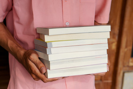 Male hand holding a stack of books. Education and knowledge concept. Portrait of young man book...