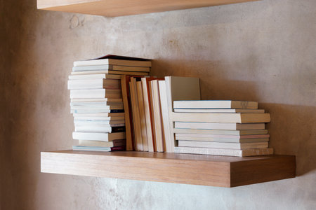 Stack of books on floating wooden bookshelf. Education and knowledge concept. Pile of books to read. House interior decorationの写真素材