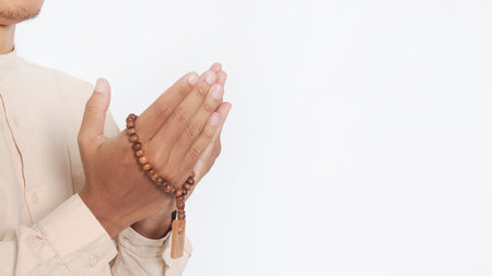 Close up portrait of religious Asian muslim man in koko shirt with skullcap praying earnestly with...