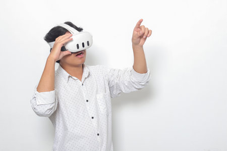Portrait of Asian man using virtual reality VR device, experiencing immersive technology. Isolated image on white backgroundの写真素材
