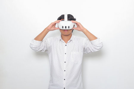Portrait of Asian man using virtual reality VR device, experiencing immersive technology. Isolated image on white backgroundの写真素材