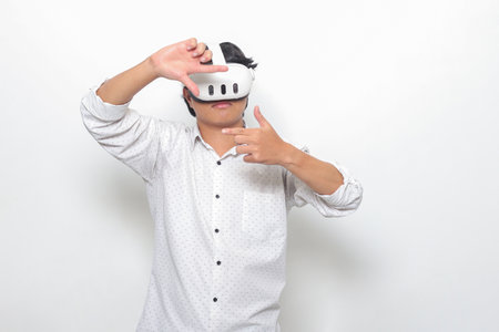 Portrait of Asian man using virtual reality VR device, experiencing immersive technology. Isolated image on white backgroundの写真素材