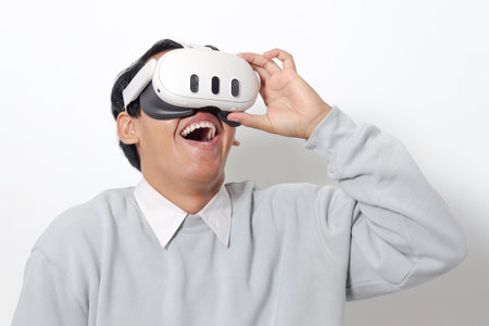 Portrait of Asian man using virtual reality VR device, experiencing immersive technology. Isolated image on white backgroundの写真素材