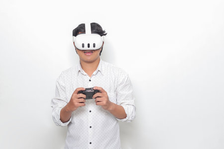 Portrait of Asian man using virtual reality VR device, playing games with console. Isolated image on white backgroundの写真素材