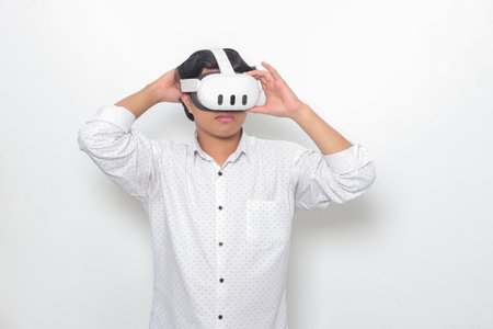 Portrait of Asian man using virtual reality VR device, experiencing immersive technology. Isolated image on white backgroundの写真素材