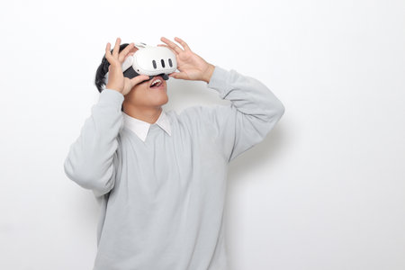 Portrait of Asian man using virtual reality VR device, experiencing immersive technology. Isolated image on white backgroundの写真素材