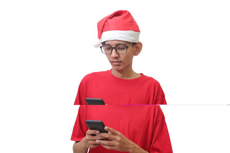 Portrait of Asian man in red t-shirt with santa hat holding mobile phone. Advertising concept. Isolated image on white backgroundの写真素材