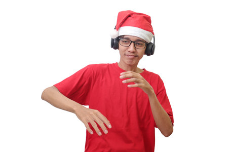 Portrait of excited Asian man in red t-shirt with santa hat enjoying and listening to music using headphone. Isolated image on white backgroundの写真素材