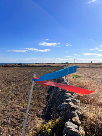 A red and blue warning flag in a field with a blue skyの写真素材