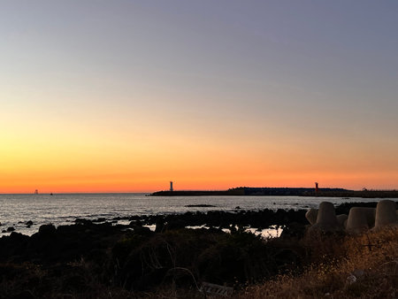 Sunset at the sea with a lighthouse in the foreground, Italyの写真素材