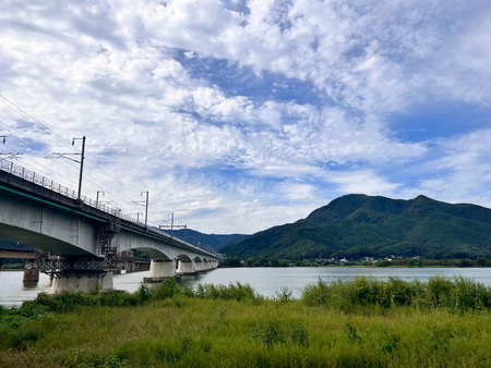 Bridge over the river with blue sky and green grass and mountains.の写真素材
