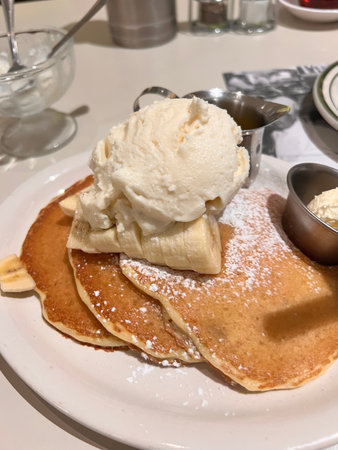 Pancakes with ice cream on a white plate in a restaurant