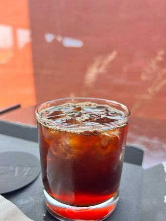 Cola with ice cubes in a glass on a table in a cafe