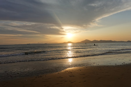 Sunset at the beach with silhouettes of people on the horizonの写真素材