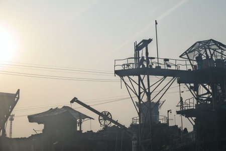 Industrial landscape in the evening. Silhouettes of cranes and workers.