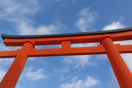 Red torii gate of Japanese temple against blue sky with clouds.の写真素材