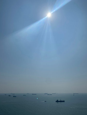 sunbeam over the sea with ships in the background and blue sky