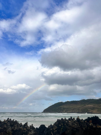 Rainbow over the ocean on a cloudy day in New Zealand.の写真素材