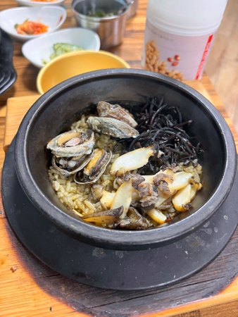 Rice with seafood and vegetables in black pot on wooden table.の写真素材