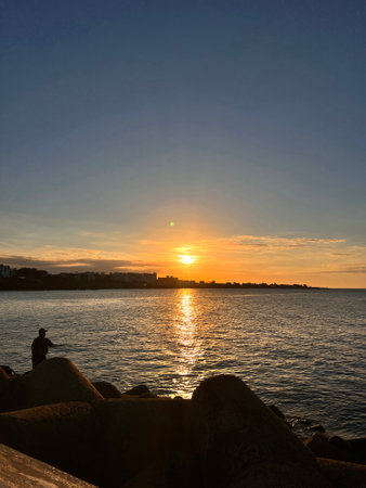 Sunset over the sea with a silhouette of a man and a womanの写真素材