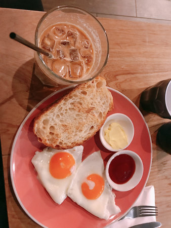 Breakfast with coffee and fried eggs in a red plate on a wooden table