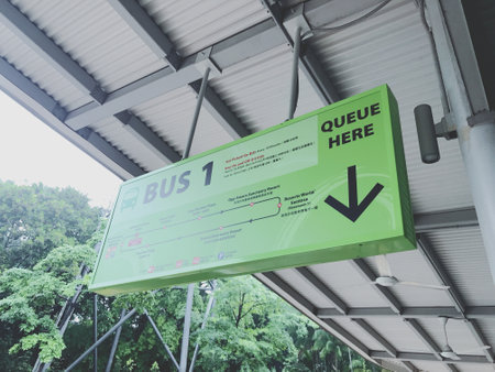 Green signboard at the bus stop with arrow pointing to the rightの写真素材