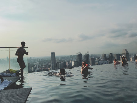 Group of friends relaxing in swimming pool with city view in the backgroundの写真素材