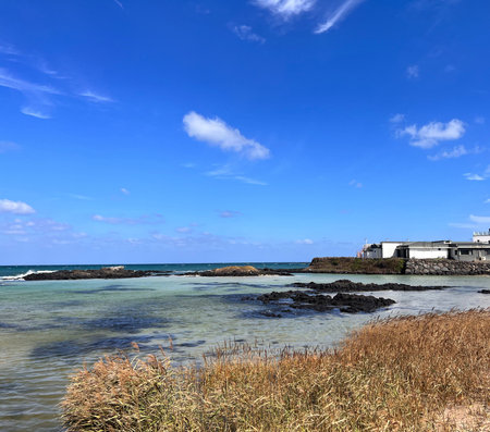 Rocky coast of the sea under blue sky with white clouds.