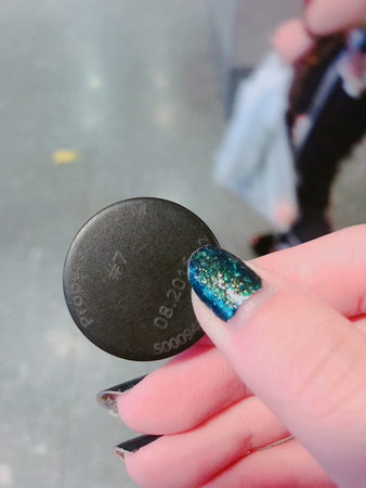 Female hand with long nails and blue manicure holding black nail polish