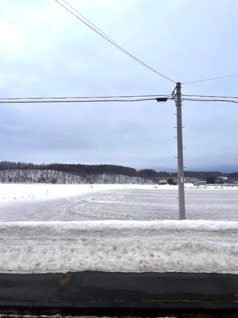 winter landscape with snow-covered road and electric pole in the foregroundの写真素材