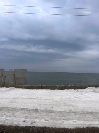 Snow on the shore of the Mediterranean Sea in cloudy weather in winterの写真素材
