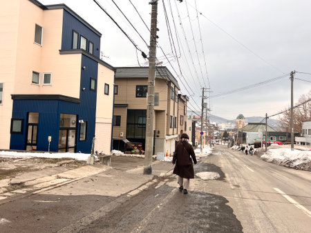 Unidentified woman walks along the street.の写真素材