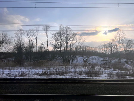 Train tracks in the winter forest at sunset. View from the train window.