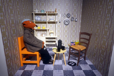 Man in a hat with a mask on his face sits in an armchair in the kitchenの写真素材