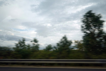 Abstract blurred motion of car on road in the countryside with cloudy skyの写真素材