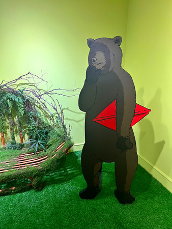 Black bear with a red arrow in his hand on a green lawn