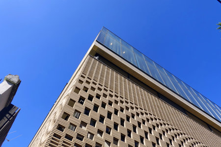 Low angle view of a modern office building with blue sky in the background