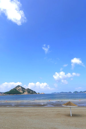 Beach umbrella and sand with blue sky and cloud, closeup of photoの写真素材