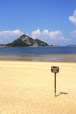 Beach sign on a sunny day with a mountain in the backgroundの写真素材