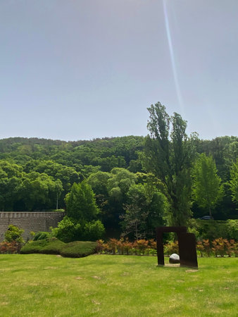 Landscape view of a park with trees and a stone wall.