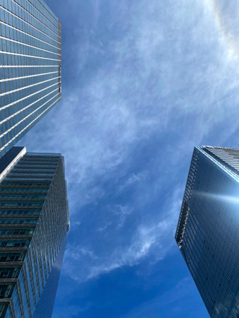 Low angle view of skyscrapers in business district against blue skyの写真素材