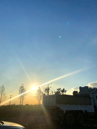 Sunset in the city, the sun shines through the clouds.の写真素材