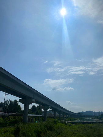 Highway viaduct under the blue sky with clouds and sun